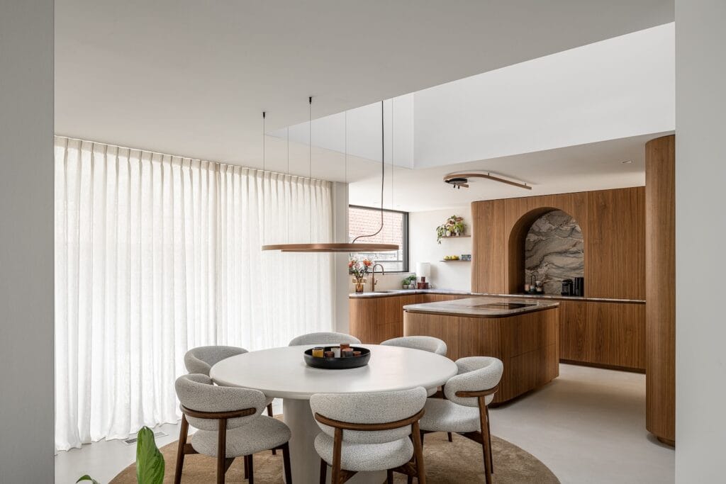 Moderne keuken met ronde tafel en stoelen, bruin hout en marmeren werkblad