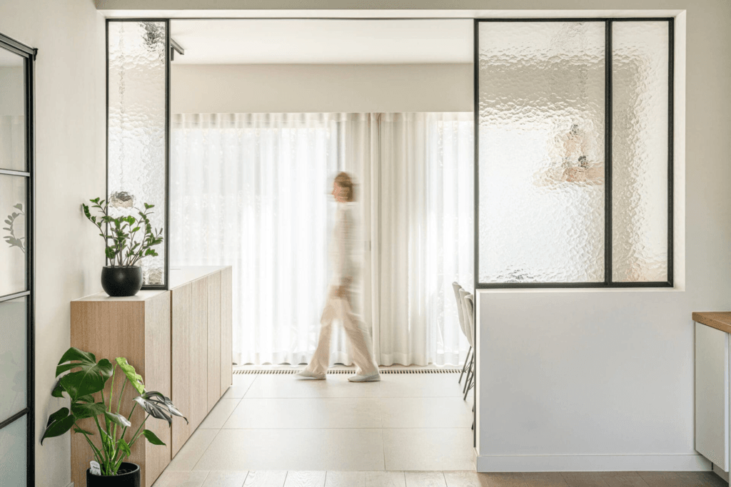 interieur in hal met veel glas en planten en wandelende vrouw
