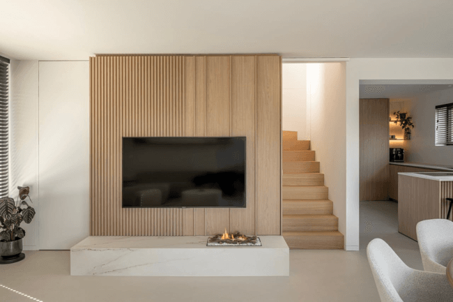 moderne leefruimte in hout met grote tv en houten trap