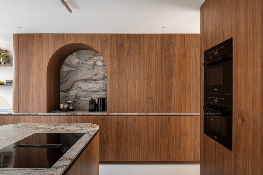 moderne strakke keuken in donker hout met groen grijs marmer, zwarte ovens en kookplaat